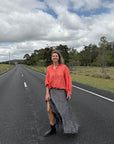 Woman standing on a road wearing estilo emporio with a cloudy sky and trees in the background