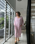 Woman in a pink dress walking through a modern home interior wearing estilo emporio dress.