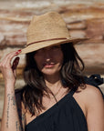 Person wearing Made in Mada Hat ELYA TAN LEATHER linen dress LUXAMORE