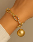 Orna Curio Golden Years Gold Plated Bracelet - LUXAMORE -Bracelets-Gold Plated Bracelet The perfect bracelet Introducing the 'Golden Years' Bracelet, a heartfelt homage to the legendary David Bowie. Crafted in stunning gold-plated alloy, this bracelet stands as a statement piece on its own or offers the canvas for your creativity with the addition of your favorite charms. It showcases a captivating hanging ball and a bold large link chain. Materials: Gold Plated Alloy Measurements: 18cm