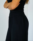 Person wearing a black dress against a plain background