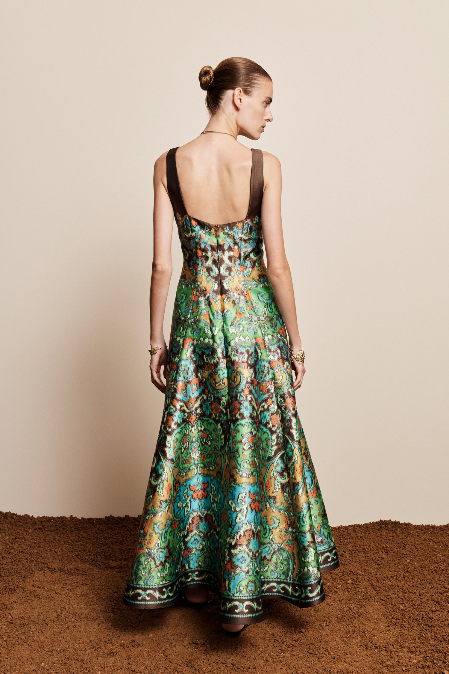 Woman wearing the ALEMAIS sustainable Charlotte Gown, a flowing maxi-length dress featuring intricate floral print details and draped long sleeves.. LUXAMORE