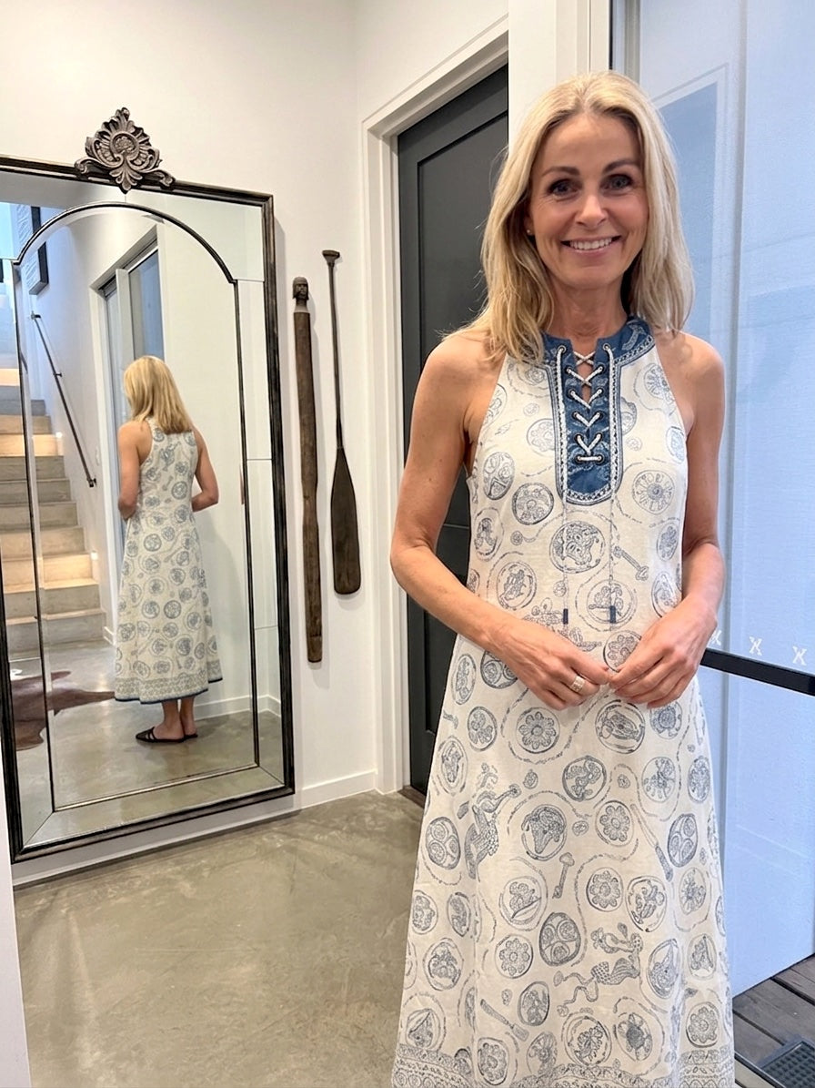 Woman wearing alemais patterned dress standing in front of a mirror.