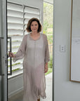 Woman walking through a modern interior with white shutters and minimal decor wearing estilo emporio dress .
