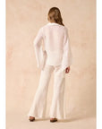 Woman wearing Estilo Emporio Linen  white outfit with flared pants against a beige background