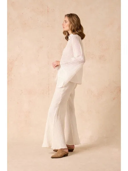 Woman wearing a Estilo Emporio linen white outfit against a beige background