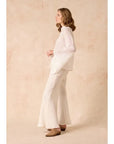 Woman wearing a Estilo Emporio linen white outfit against a beige background