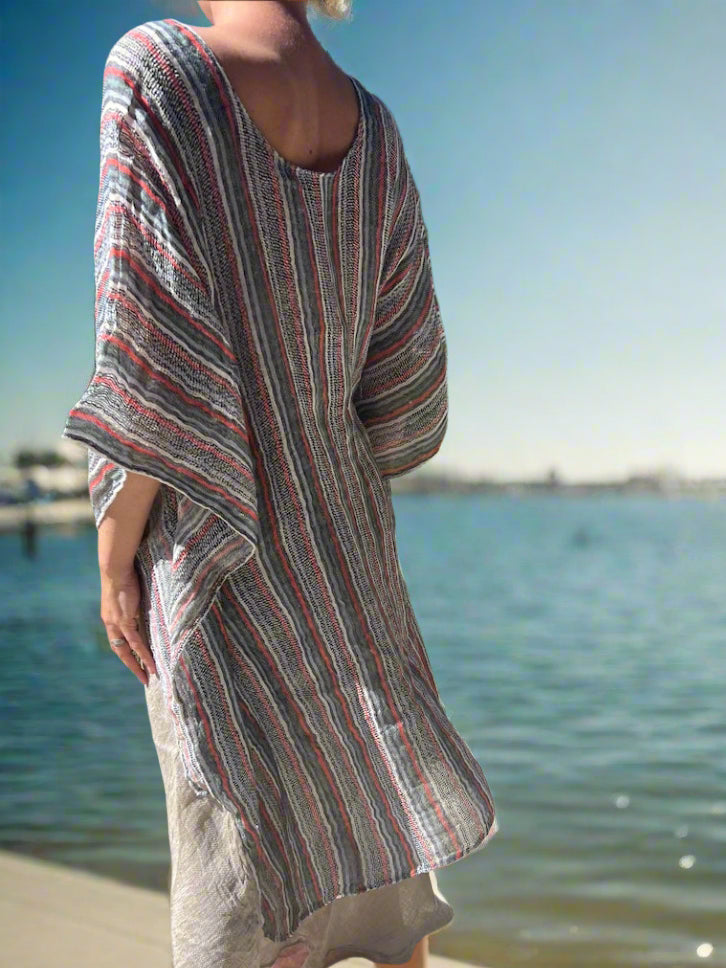 Person wearing a striped dress standing on a concrete path with grass and trees in the background