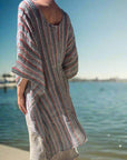 Person wearing a striped dress standing on a concrete path with grass and trees in the background