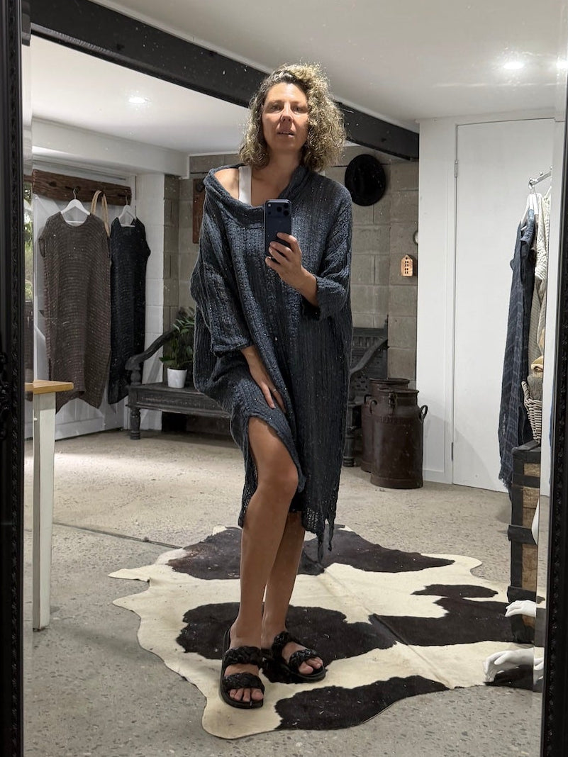 Person standing in a room with a large black-framed mirror, wearing a la bottega di brunella linen dress.