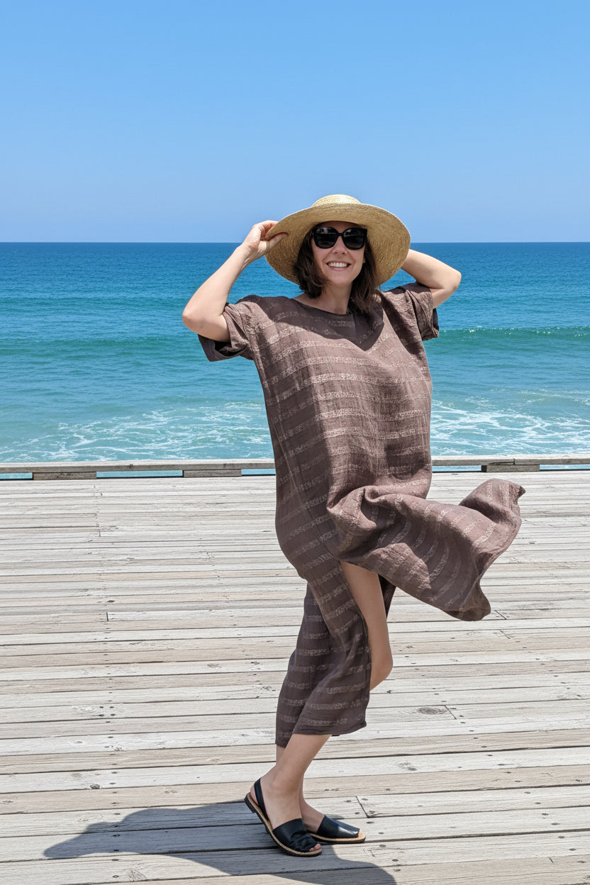 la bottega di brunella dress and person wearing wide-brimmed hat and sunglasses on a boardwalk by the ocean. 