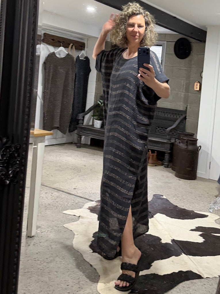 Person wearing a long, la bottega di brunealla navy linen dress with a slit, standing in front of a full-length mirror in a clothing store.
