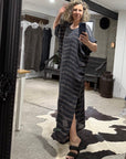 Person wearing a long, la bottega di brunealla navy linen dress with a slit, standing in front of a full-length mirror in a clothing store.