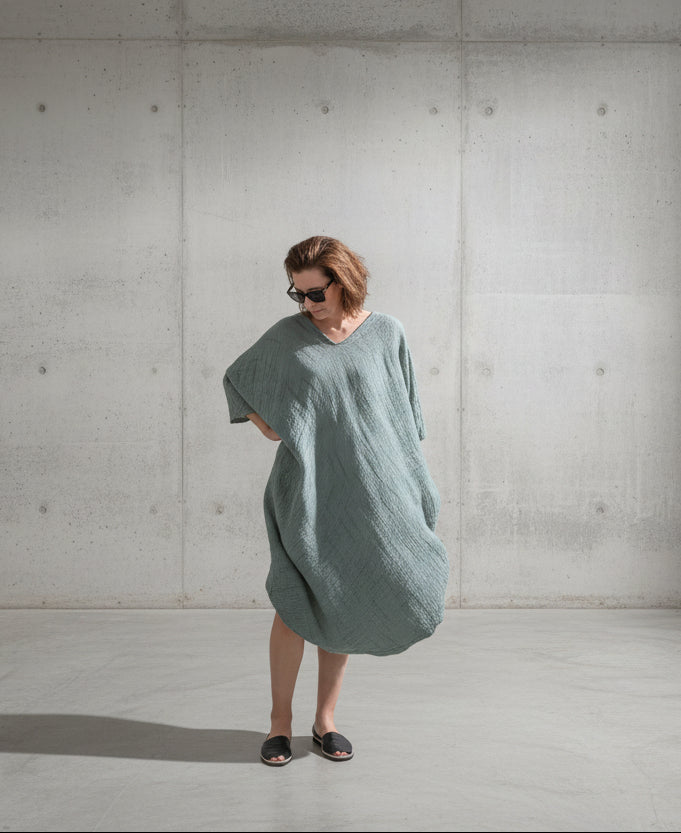 Person standing by a pool with a scenic coastal town in the background