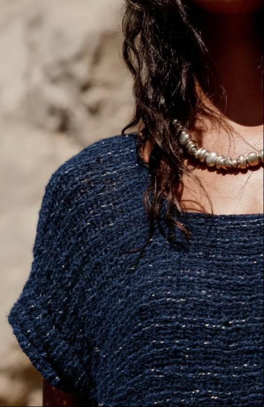 Close-up of a person wearing a textured blue top with a blurred background