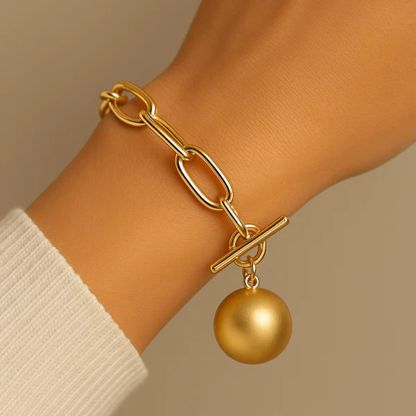 Orna Curio Golden Years Gold Plated Bracelet - LUXAMORE -Bracelets-Gold Plated Bracelet The perfect bracelet Introducing the 'Golden Years' Bracelet, a heartfelt homage to the legendary David Bowie. Crafted in stunning gold-plated alloy, this bracelet stands as a statement piece on its own or offers the canvas for your creativity with the addition of your favorite charms. It showcases a captivating hanging ball and a bold large link chain. Materials: Gold Plated Alloy Measurements: 18cm