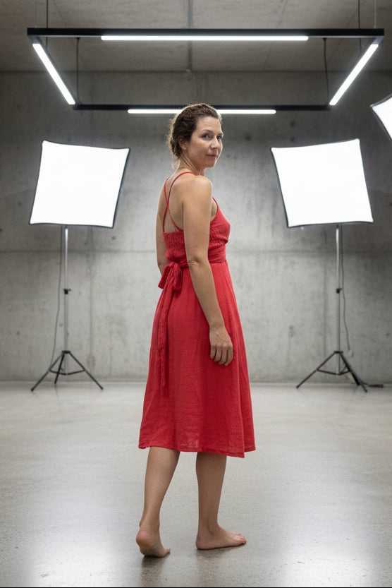 Woman in a red dress standing in a studio with lighting equipment.