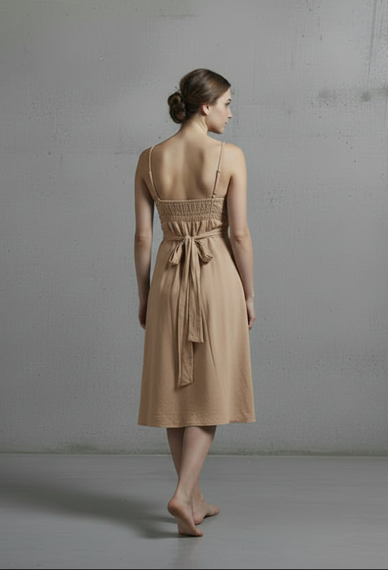 Person wearing a red dress standing against a plain gray wall.