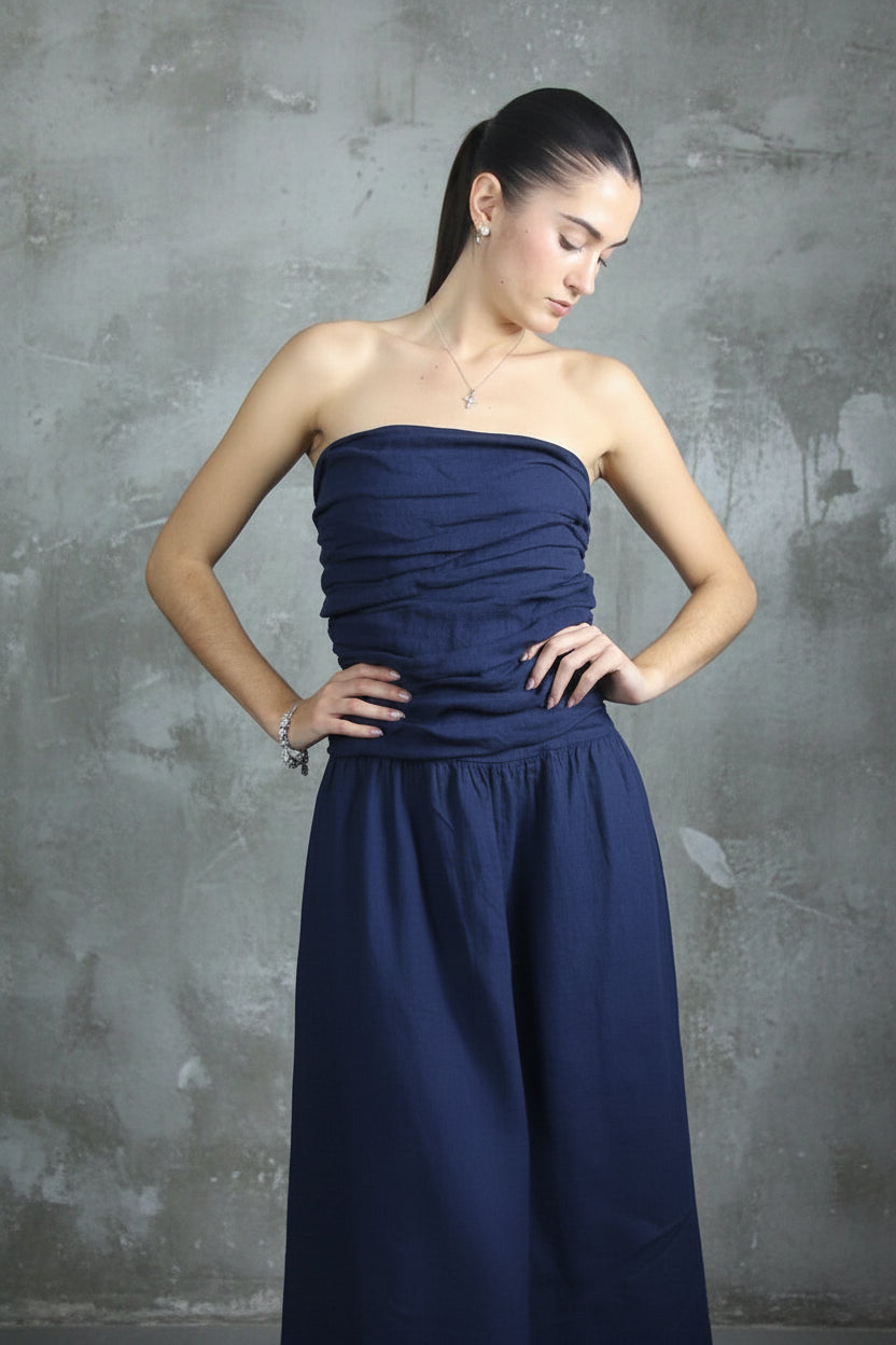Woman wearing a italian linen dress navy strapless against a light curtain background