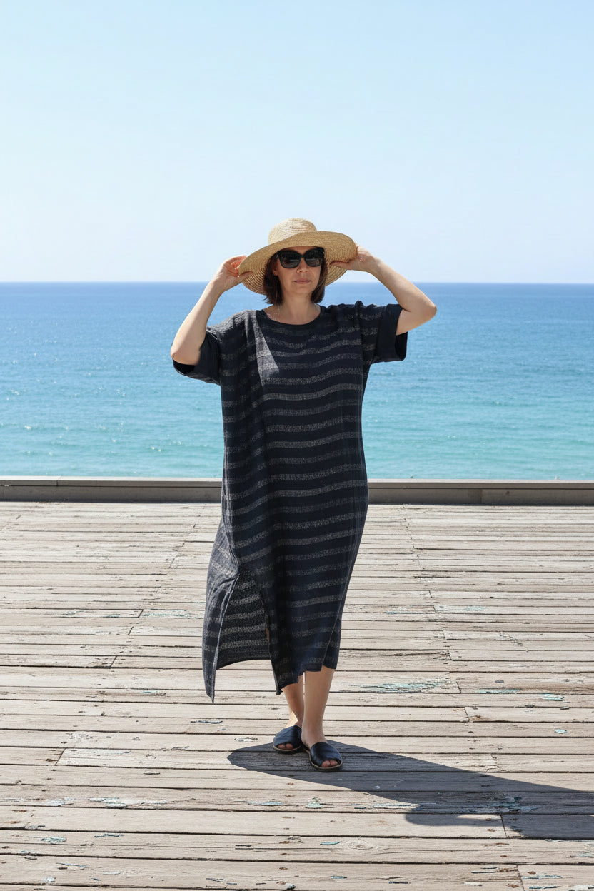 Person wearing la bottega di brunella linen dress and hat on a boradwalk by the ocean